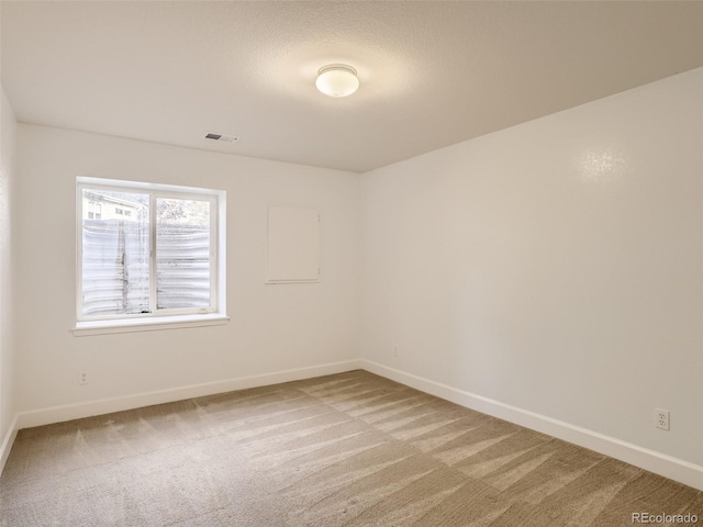 spare room featuring light colored carpet, baseboards, and visible vents