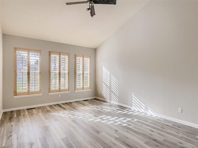 spare room featuring baseboards, light wood finished floors, ceiling fan, and vaulted ceiling