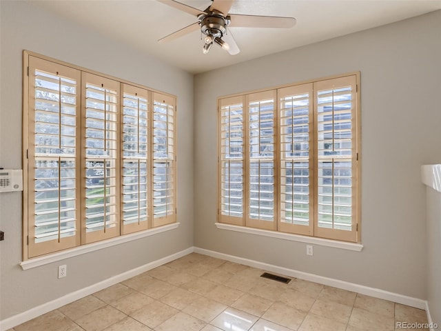 tiled spare room with visible vents, a ceiling fan, and baseboards