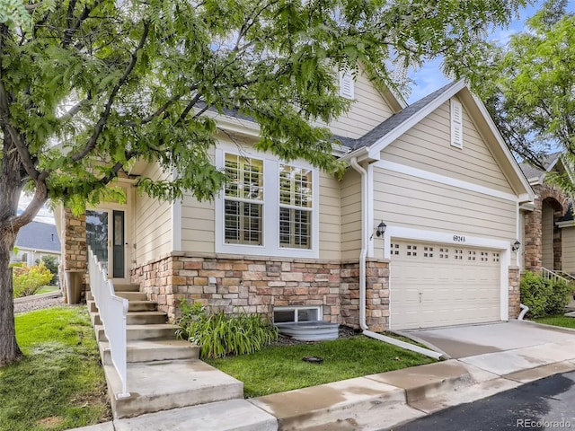 view of front of home featuring driveway, a shingled roof, and stone siding
