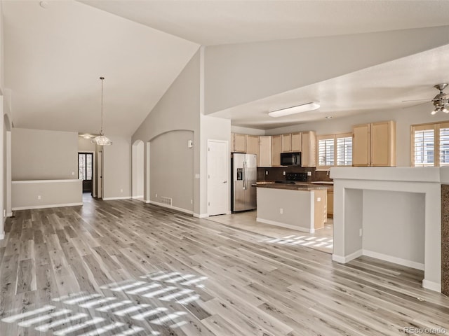 unfurnished living room featuring visible vents, light wood-style floors, baseboards, high vaulted ceiling, and ceiling fan with notable chandelier
