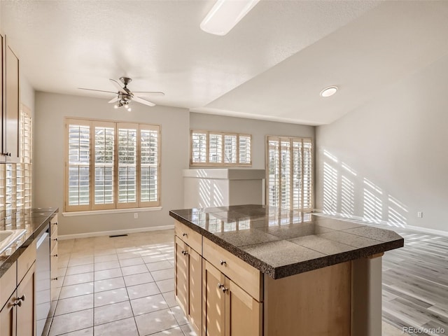 kitchen with a ceiling fan, tile countertops, stainless steel dishwasher, light tile patterned floors, and baseboards