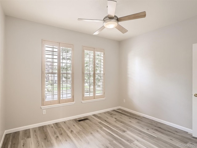 spare room featuring baseboards, ceiling fan, wood finished floors, and visible vents