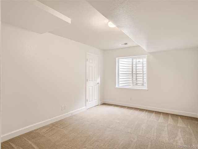 unfurnished room with a textured ceiling, baseboards, visible vents, and carpet