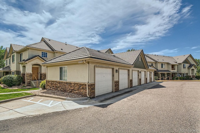 22580 E Ontario Dr Unit 202, Aurora, CO 80016 - view of front of property featuring stucco siding, stone siding, community garages, a residential view, and a tiled roof