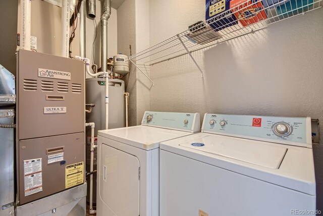 laundry room with gas water heater, heating unit, and washer and clothes dryer