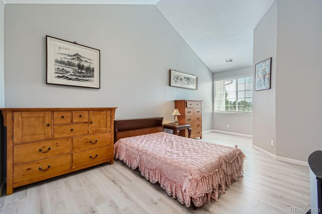 bedroom with light wood-type flooring and high vaulted ceiling