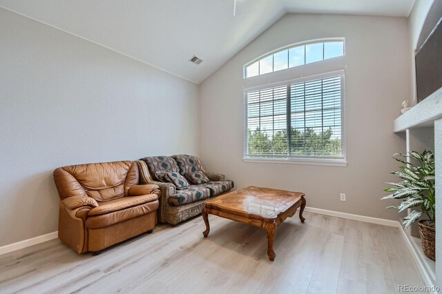 living room featuring lofted ceiling and light hardwood / wood-style floors