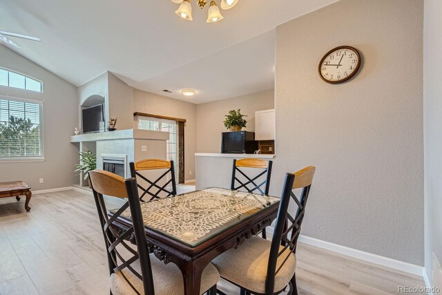 dining room with light wood-type flooring, ceiling fan, and vaulted ceiling