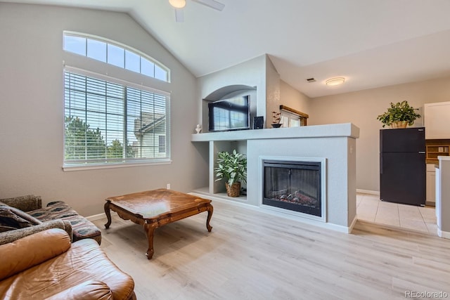 living room featuring vaulted ceiling, a wealth of natural light, light hardwood / wood-style flooring, and ceiling fan