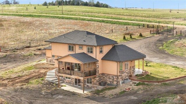 942 S County Road 129th Rd, Bennett, CO 80102 - rear view of house featuring driveway, stucco siding, stone siding, and a rural view