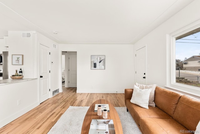 living area with baseboards, visible vents, and light wood finished floors