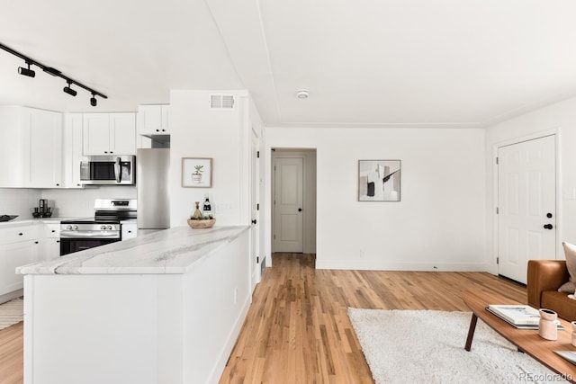 kitchen with stainless steel appliances, light wood-style flooring, decorative backsplash, white cabinets, and a peninsula