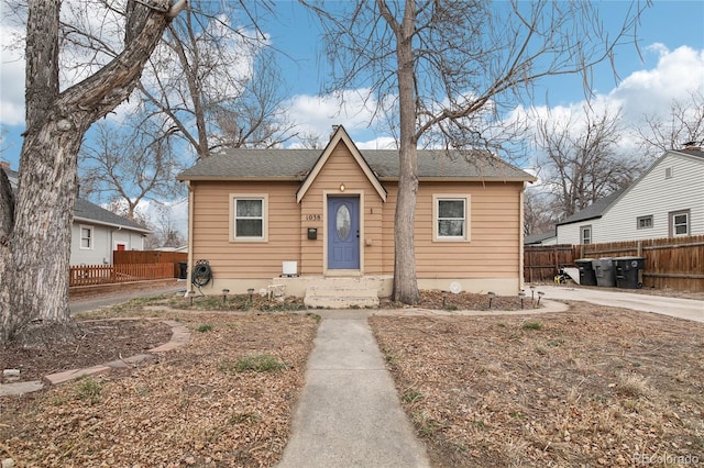 bungalow-style house featuring a shingled roof and fence