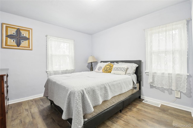 bedroom featuring visible vents, baseboards, and wood finished floors