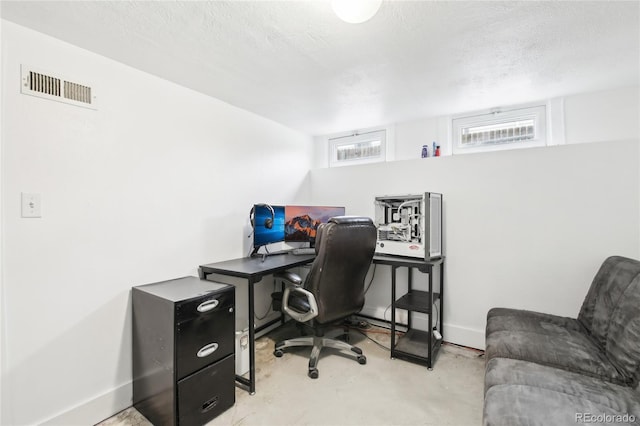 office featuring baseboards, visible vents, concrete flooring, and a textured ceiling