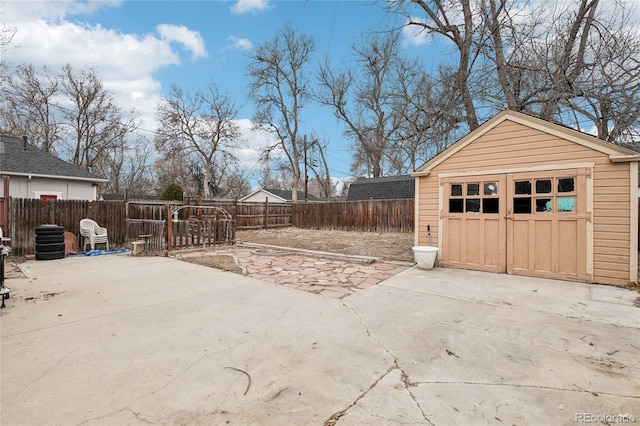 detached garage featuring driveway and fence