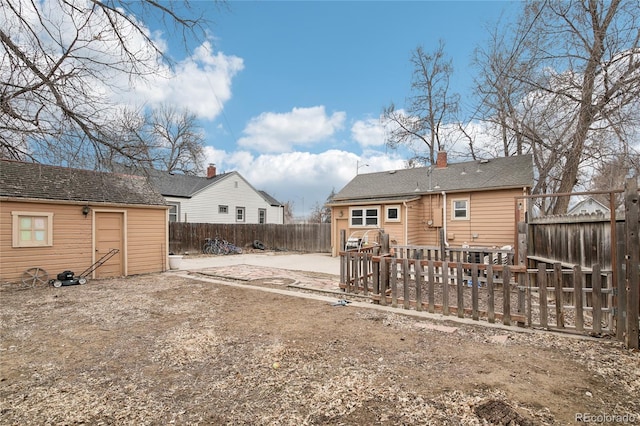 back of house with an outbuilding, a chimney, and a fenced backyard