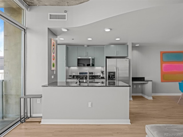 891 14th St Unit 2505, Denver, CO 80202 - kitchen with appliances with stainless steel finishes, dark countertops, a sink, a peninsula, and light wood-style floors