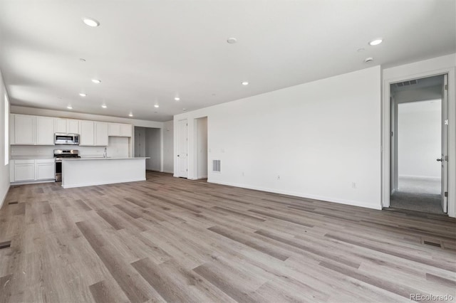 19040 E 96th Pl, Commerce City, CO 80022 - unfurnished living room with recessed lighting, light wood-type flooring, baseboards, and a sink