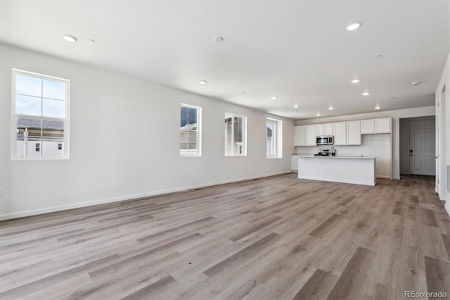 19040 E 96th Pl, Commerce City, CO 80022 - unfurnished living room featuring plenty of natural light, light wood-type flooring, recessed lighting, and baseboards