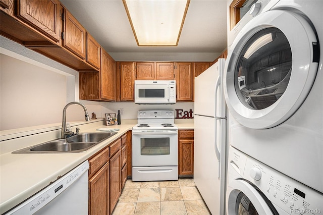 kitchen featuring stacked washer / dryer, sink, and white appliances