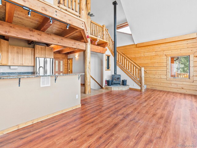11766 Coal Creek Heights Dr, Golden, CO 80403 - unfurnished living room featuring a wood stove, track lighting, light wood-type flooring, stairway, and high vaulted ceiling
