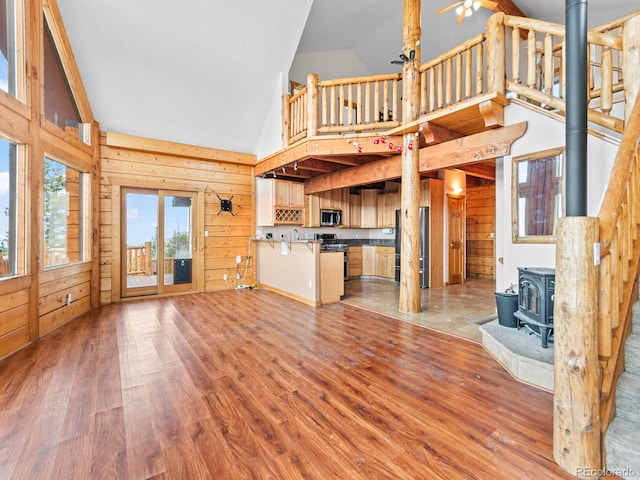 11766 Coal Creek Heights Dr, Golden, CO 80403 - unfurnished living room with high vaulted ceiling, a wood stove, wood walls, wood finished floors, and a sink