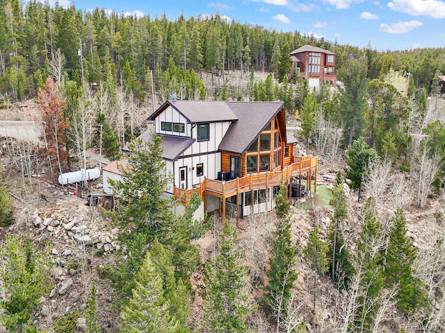 11766 Coal Creek Heights Dr, Golden, CO 80403 - rear view of house with board and batten siding, a wooded view, and a deck