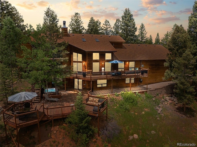 192 Nova Dr, Pine, CO 80470 - back of house at dusk featuring a wooden deck, a chimney, and roof with shingles