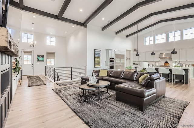 living room featuring beamed ceiling, high vaulted ceiling, a notable chandelier, and light wood-type flooring