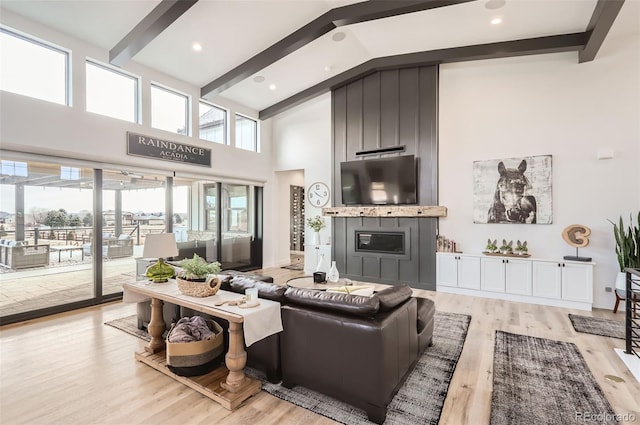 living room featuring beamed ceiling, high vaulted ceiling, a fireplace, and light hardwood / wood-style floors