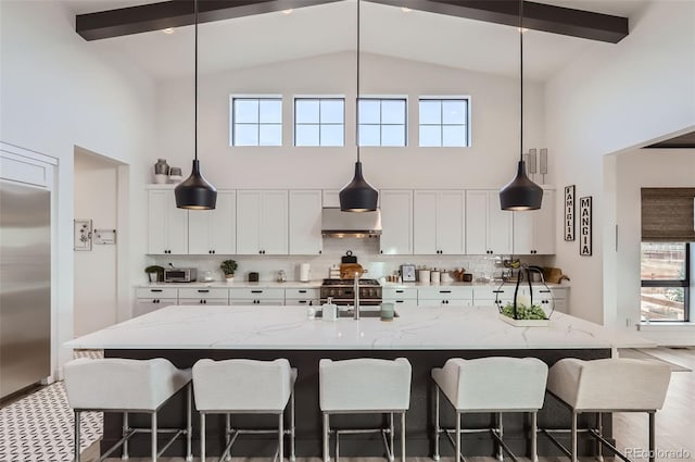 kitchen featuring light stone counters, wall chimney exhaust hood, and a kitchen island with sink