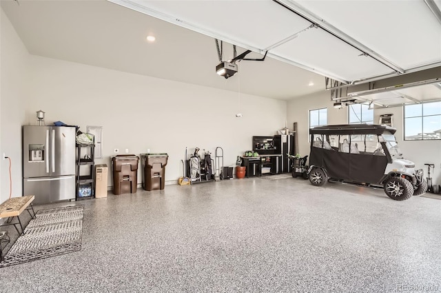 garage with a garage door opener and stainless steel refrigerator with ice dispenser