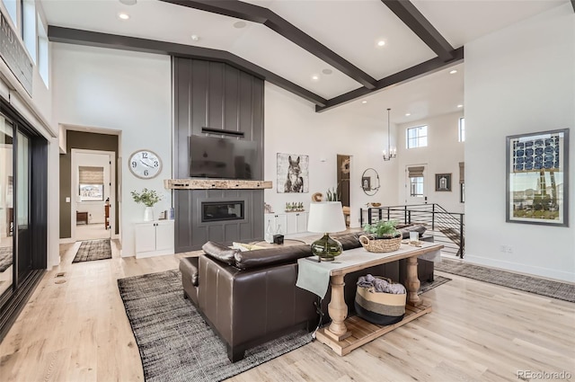 living room with light hardwood / wood-style flooring, a fireplace, high vaulted ceiling, and beamed ceiling