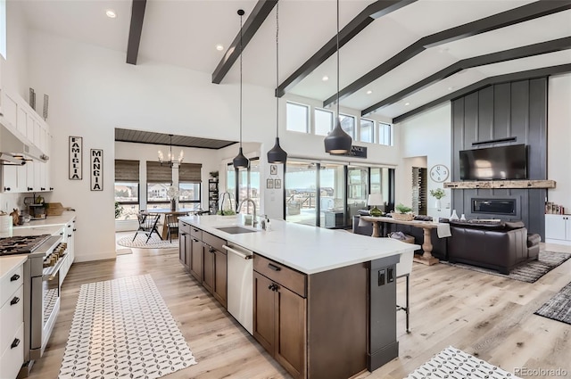 kitchen featuring sink, an island with sink, pendant lighting, stainless steel appliances, and white cabinets