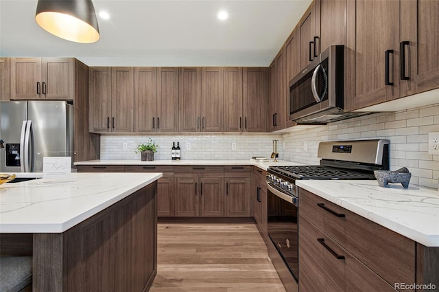 4127 Tejon St, Denver, CO 80211 - kitchen with stainless steel appliances, light wood-type flooring, decorative backsplash, and light stone counters