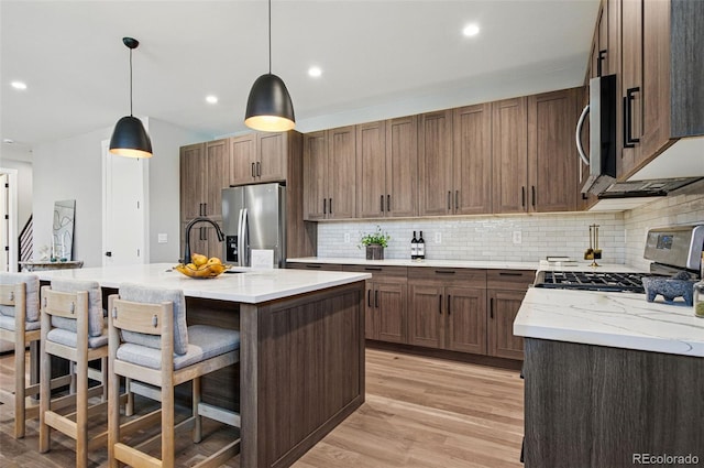 4127 Tejon St, Denver, CO 80211 - kitchen featuring stainless steel appliances, light wood-type flooring, backsplash, a breakfast bar, and hanging light fixtures