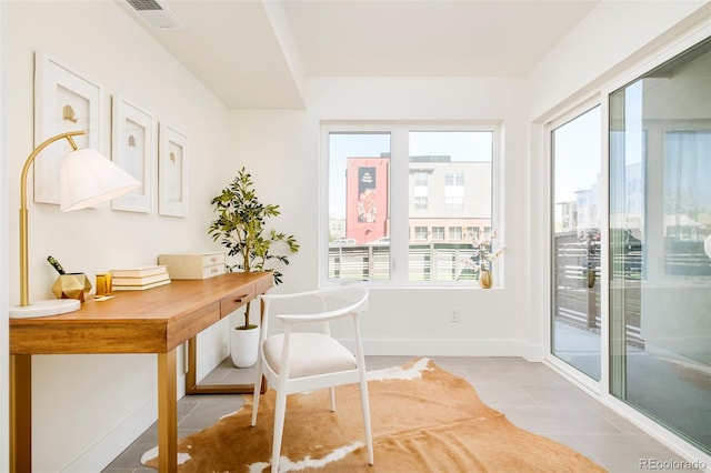 office space featuring tile patterned floors, visible vents, baseboards, and a wealth of natural light