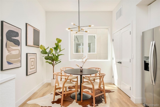 dining area featuring light wood-style floors, baseboards, a notable chandelier, and visible vents