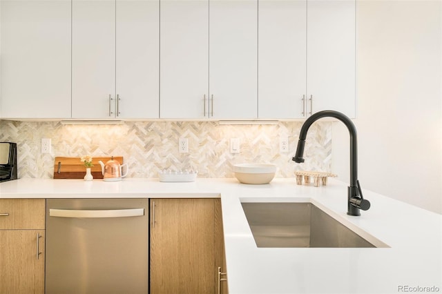 kitchen featuring backsplash, stainless steel dishwasher, a sink, light countertops, and white cabinets