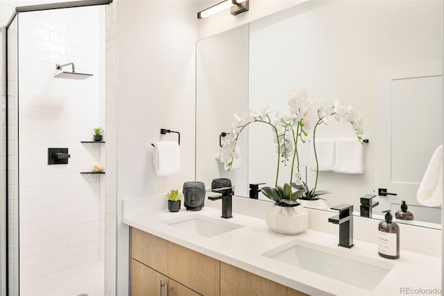bathroom with double vanity, a sink, and a tile shower