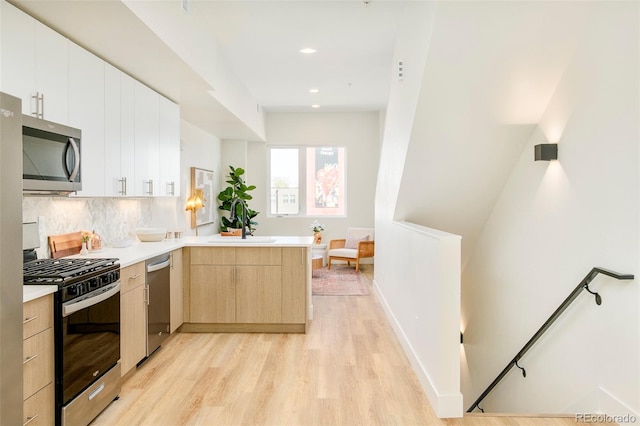 2105 S Galapago St Unit 4, Denver, CO 80223 - kitchen featuring appliances with stainless steel finishes, a peninsula, light wood-style flooring, light countertops, and recessed lighting