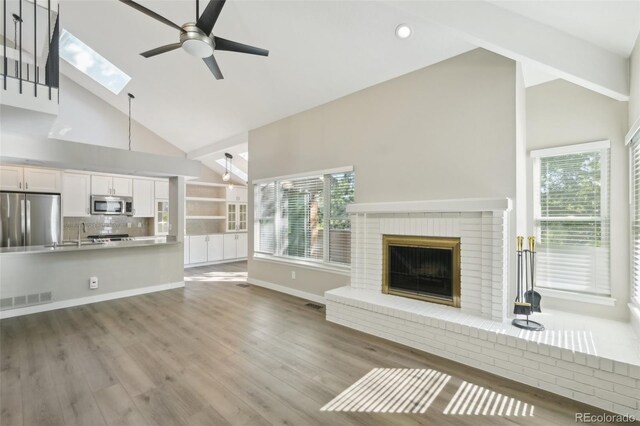 9455 W 81st Ave Unit A, Arvada, CO 80005 - unfurnished living room featuring high vaulted ceiling, ceiling fan, a brick fireplace, plenty of natural light, and recessed lighting