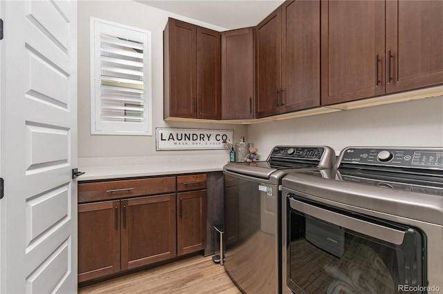 clothes washing area featuring cabinet space, light wood finished floors, and washer and dryer