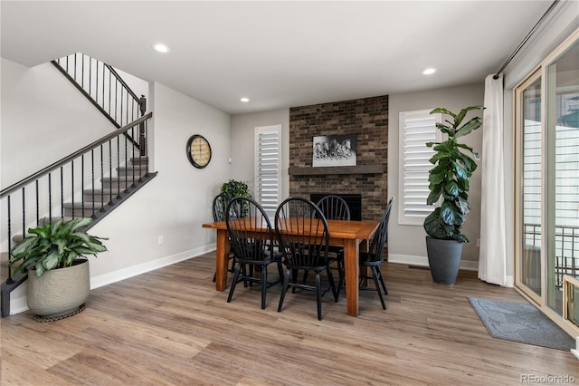 dining area with recessed lighting, a brick fireplace, stairway, and wood finished floors