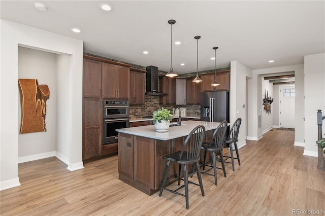 kitchen featuring stainless steel double oven, high end fridge, wall chimney range hood, light countertops, and decorative backsplash