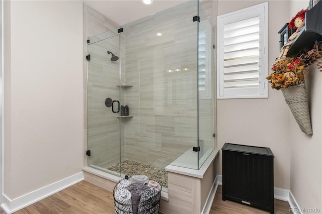 full bath with a stall shower, wood finished floors, and baseboards