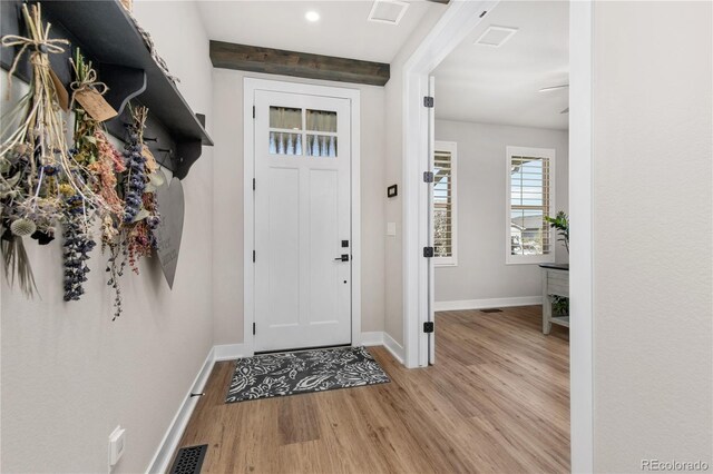 foyer entrance featuring baseboards, visible vents, and wood finished floors