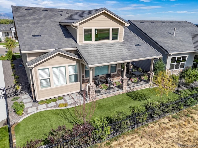 view of front facade featuring a tiled roof, a front lawn, a fenced backyard, and a patio